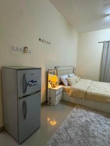 a small bedroom with a bed and a refrigerator at غرفة vip فخمة للإيجار اليومي او الأسبوعي او الشهري في الخوض السادسة in Al Khawḑ