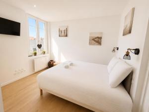 a white bedroom with a bed and a window at La Chambre Deauvillaise in Deauville