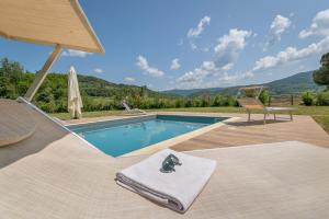 a swimming pool with a towel and a chair next to it at Villa Adelmo appartamento privato in Pomarance
