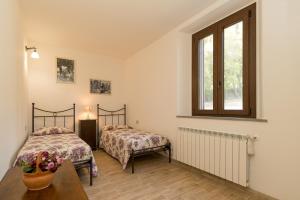 a bedroom with two beds and a table and a window at Villa Adelmo appartamento privato in Pomarance