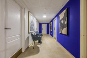 a corridor with blue walls and chairs in a hallway at UP Hotel Velilla in Velilla de San Antonio