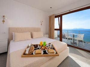 a tray of food on a bed with a view of the ocean at Hill Suites in Vlorë