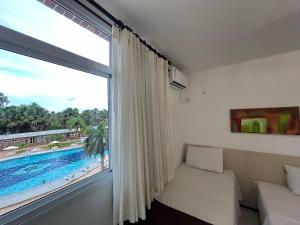 a room with a large window with a view of a pool at Gran Lençóis Flat Residence - Flat 302 in Barreirinhas +23 photos
