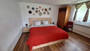 a bedroom with a large bed with a red blanket at La numărul 100, Nămăești in Nămăeşti