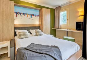 a bedroom with a large bed with a painting on the wall at Residence Pierre & Vacances Les Embruns in Deauville +24 photos