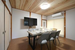 a dining room with a table with chairs and a television at The CATAN 宮津 in Yura