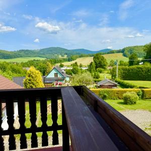 a wooden bench on a balcony with a view of the mountains at Vila Bělá pod Pradědem in Bělá pod Pradědem