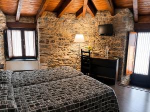a bedroom with a bed and a stone wall at Hostal Ultreia in Villafranca del Bierzo