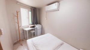 a small white room with a bed and a window at 1971 Sinpung Inn in Seoul