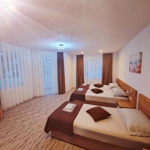 a hotel room with three beds and windows at Къща за гости КрисиЯна in Zlatograd