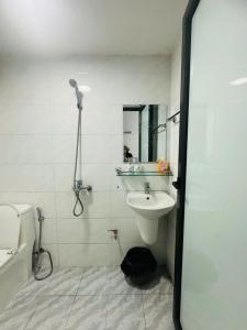 a white bathroom with a sink and a shower at Harmony Apartment in Hanoi