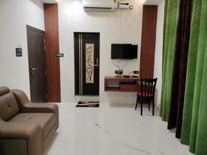 a living room with a couch and a desk and a television at Hotel Raj in Letekujān