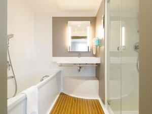 a bathroom with a tub and a sink and a shower at Novotel Suites Nancy Centre in Nancy +53 photos
