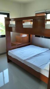 a bedroom with a bunk bed with white sheets at Triple J Villa Puerto Galera in Puerto Galera