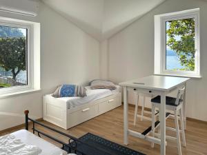 a bedroom with a bed and a desk and two windows at Casa Caprice in Cannero Riviera +9 photos