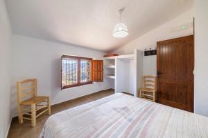 a bedroom with a bed and two chairs and a window at Yerbaluisa in Laroya +27 photos
