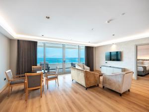a living room with a table and chairs and a bedroom at Korumar Hotel Deluxe in Kuşadası