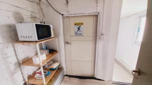 a microwave sitting on a shelf next to a door at 1971 Sinpung Inn in Seoul