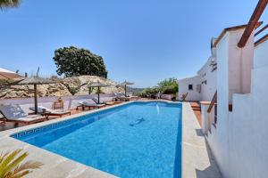 a swimming pool next to a building with chairs and a building at Casa Azafranes - Boutique B&B - Arenas in Arenas