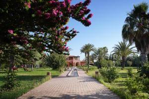 a brick path in a park with palm trees and a building at Domaine 3 Riads in Marrakesh