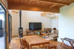 a living room with a wooden table and a couch at お子さま連れ歓迎 森のやさしいサウナ付き一棟貸し -ご家族ご夫婦限定- in Komoro