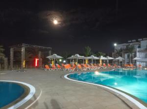 a pool at night with chairs and a roller coaster at Appartement Hotel Andalucia Bizerte in Bizerte +19 photos
