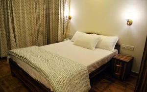 a small bedroom with a bed with white sheets and pillows at Nirvana Inn in Mahabaleshwar