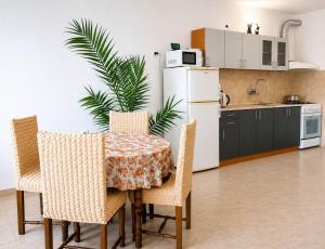 a kitchen with a table and chairs and a white refrigerator at Къща за гости Уют in Sveti Vlas
