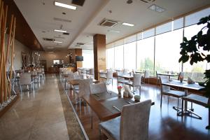 ein Restaurant mit Tischen und Stühlen und großen Fenstern in der Unterkunft Orucoglu Oreko Hotel in Manisa