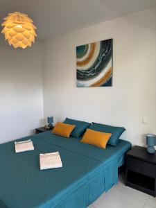 a bedroom with a blue bed with orange pillows at la mer la corse in San-Nicolao