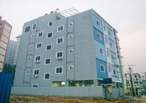 a large gray building with blue at NRI Hotels & Coliving in Hyderabad +20 photos