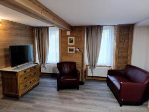 a living room with a tv and a couch and chairs at Little Flowerpot in Unterseen