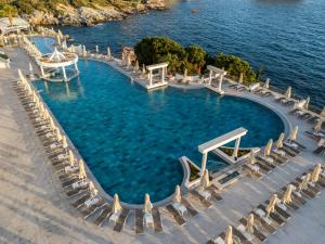 an infinity pool with chairs and the water at Korumar Hotel Deluxe in Kuşadası