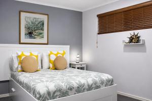 a bedroom with a bed with yellow pillows at Sea Breeze Apartment in Mandurah