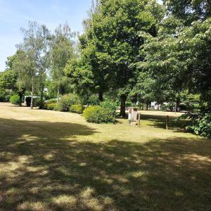a park with green grass and trees and a bench at Camping Onlycamp Veuzain-sur-Loire in Veuzain-sur-Loire