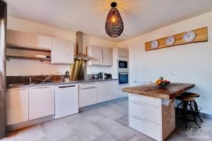 a kitchen with white cabinets and a wooden counter top at PAPANG - House 148m 3rooms Jacuzzi in Saint-Leu