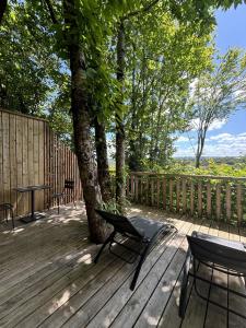 a wooden deck with two chairs and a tree at Domaine de Meros in Plonévez-du-Faou