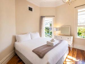a bedroom with a large white bed and a window at Crescent Villa - Stay Waiheke in Ostend