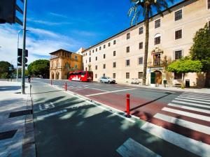 a red bus driving down a city street with a building at Alojamiento San Juan en Murcia Centro in Murcia