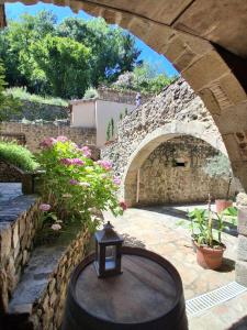 a stone archway with a table in a patio at La petite Sorbonne - Chambres d'hôtes in Malleval +24 photos
