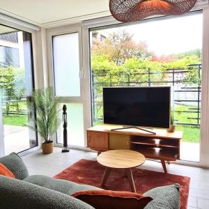 a living room with a tv and a couch and a table at Studio Premium - Jardin privatif - Parking in Epalinges