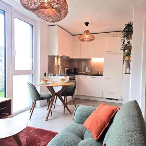 a living room with a couch and a table and a kitchen at Studio Premium - Jardin privatif - Parking in Epalinges