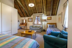 a bedroom with a bed and a couch and a table at Plotsklaps Self Catering Cottage in Tokai +37 photos