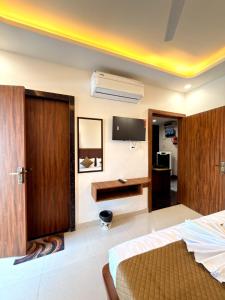 a bedroom with a bed and a tv on the wall at Hotel Shree Krishnam, Kota in Kota