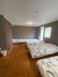three beds in a room with a wooden floor at Guest House SOL in Hiraisomachi +22 photos