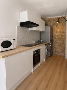a kitchen with white cabinets and a microwave at Maison Plumeria in Triel-sur-Seine
