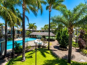 a resort with a swimming pool and palm trees at Sea Breeze Apartment in Mandurah
