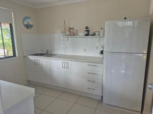 a kitchen with white cabinets and a white refrigerator at Rainbow Heights 2 Bed Apartment in Rainbow Beach