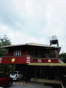 a red building with cars parked in front of it at Pine ridge homestay kuttikanam in Pīrmed +13 photos