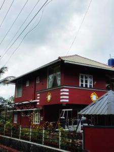 a red house with a fence in front of it at Pine ridge homestay kuttikanam in Pīrmed